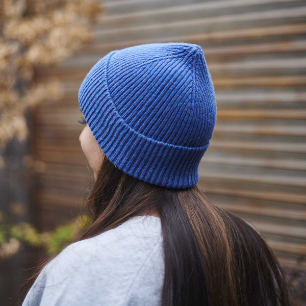 Person wearing a blue knit beanie with a blurred background