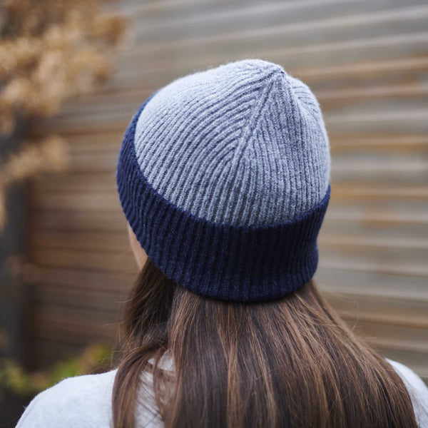 Person wearing a two-tone blue and gray knit beanie with a blurred background