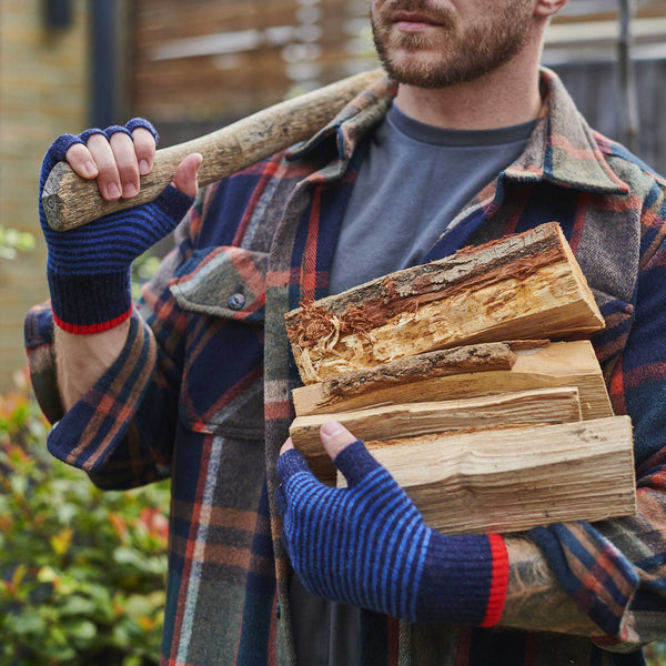 Man holding a stack of wood and an axe outdoors