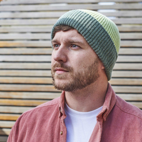 Man wearing a green and beige beanie against a wooden background