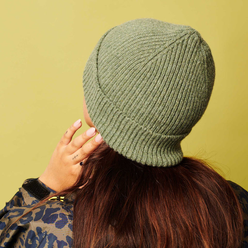 Person wearing a green knit beanie against a yellow background