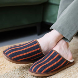 Striped slippers worn indoors on a carpeted floor.