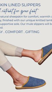 A person wearing  Catherine Tough blue sheepskin-lined slip-on slippers with beige trim and cream pants, shown against a light grey background with promotional text about comfort and warmth.