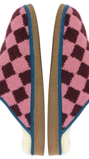 A pair of Catherine Tough knit slip-on slippers with a pink and dark burgundy argyle pattern, featuring a cream-colored sheepskin lining and a blue trim along the edge.
