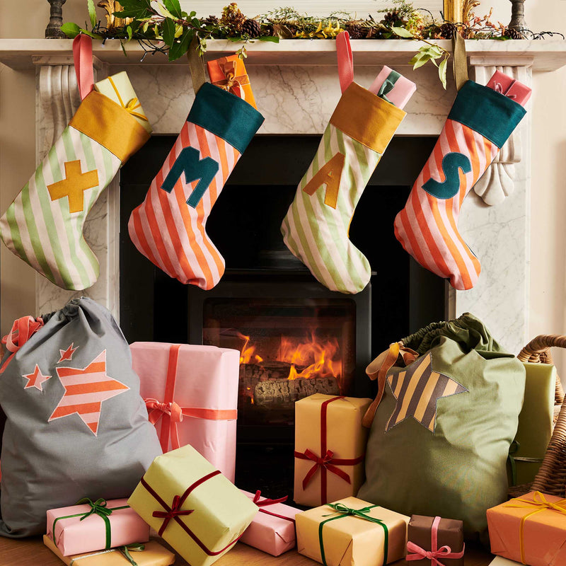 Colorful Christmas stockings hanging above a fireplace with wrapped gifts on the floor.